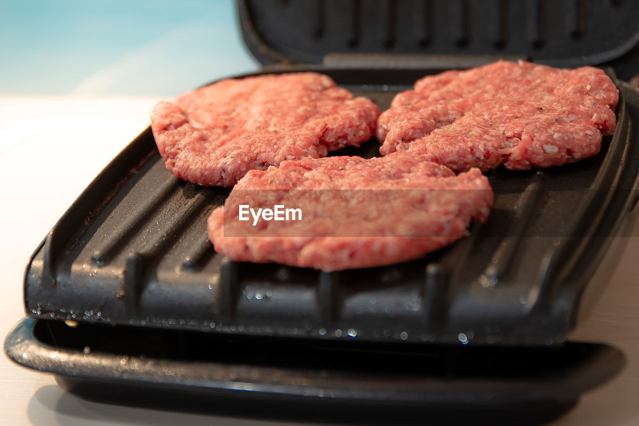 CLOSE-UP OF MEAT ON BARBECUE GRILL IN KITCHEN