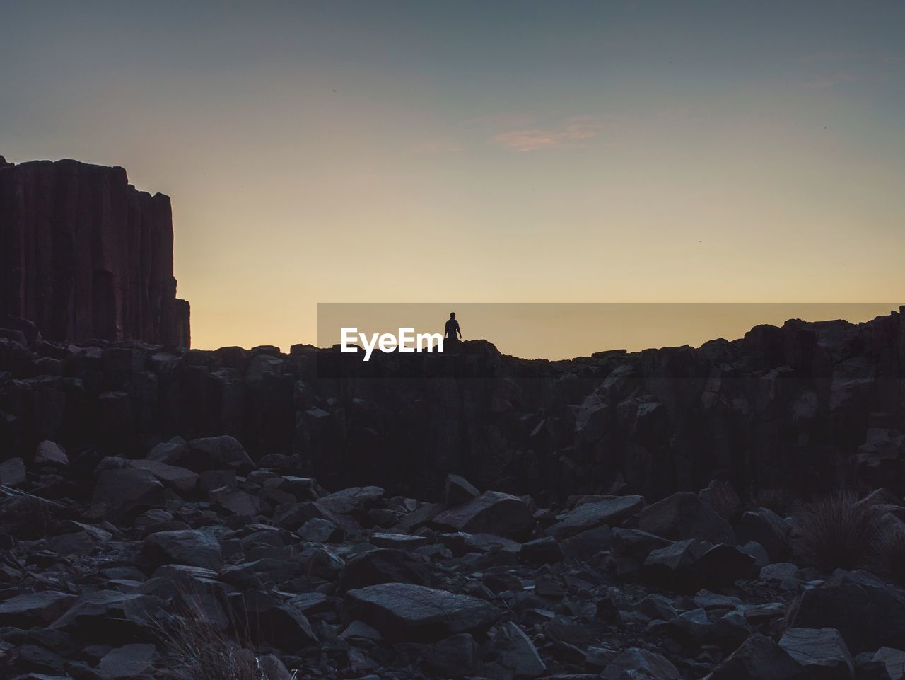 Rocks on field against sky at sunset