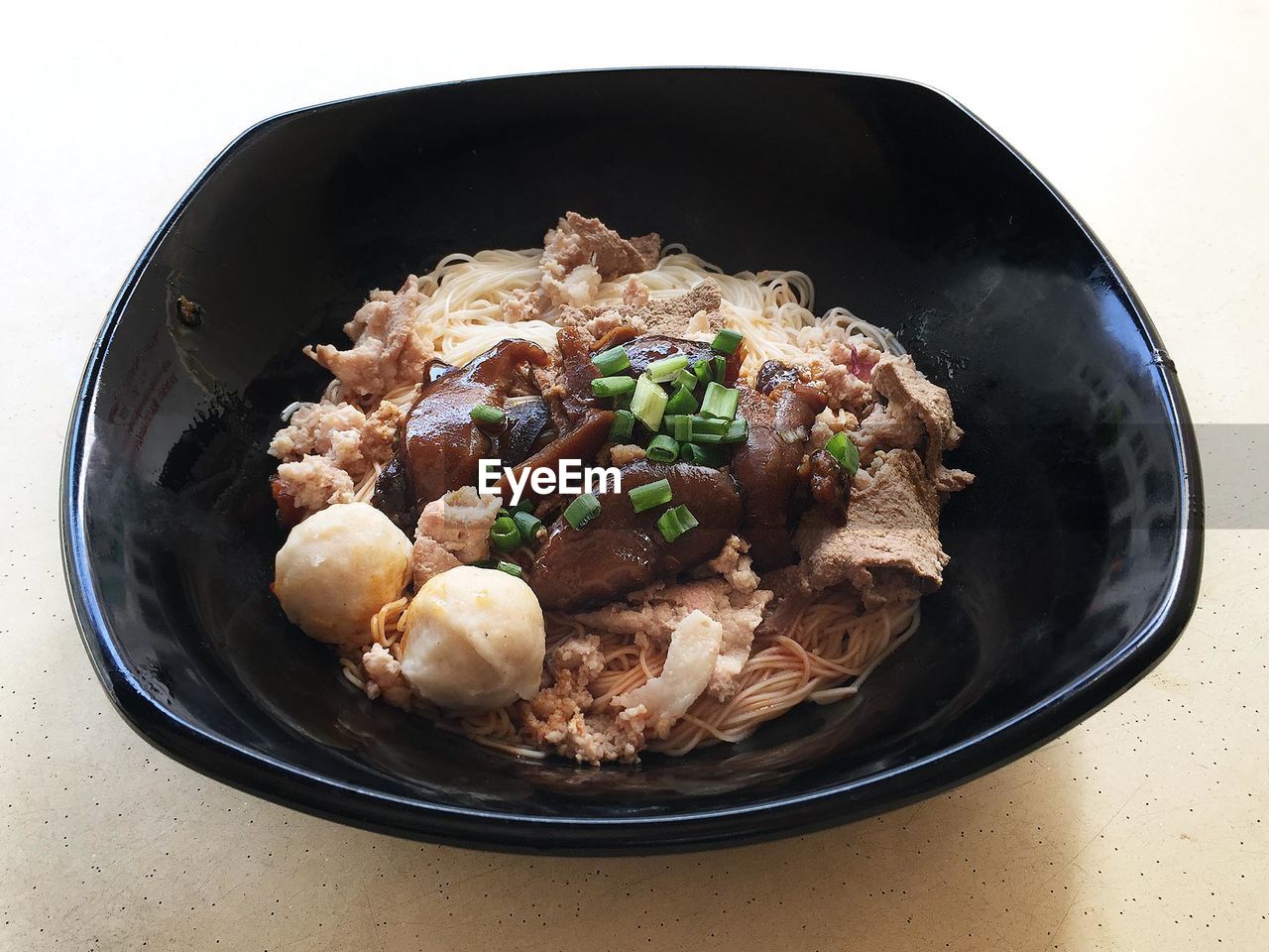 Pasta with meat and spring onion garnish