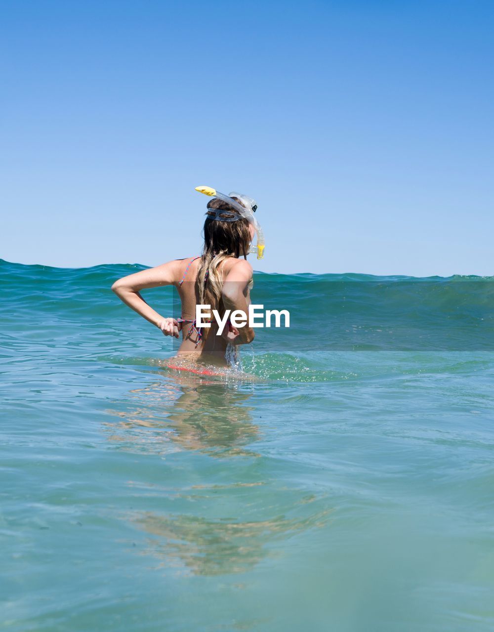 Woman snorkeling in sea against clear blue sky