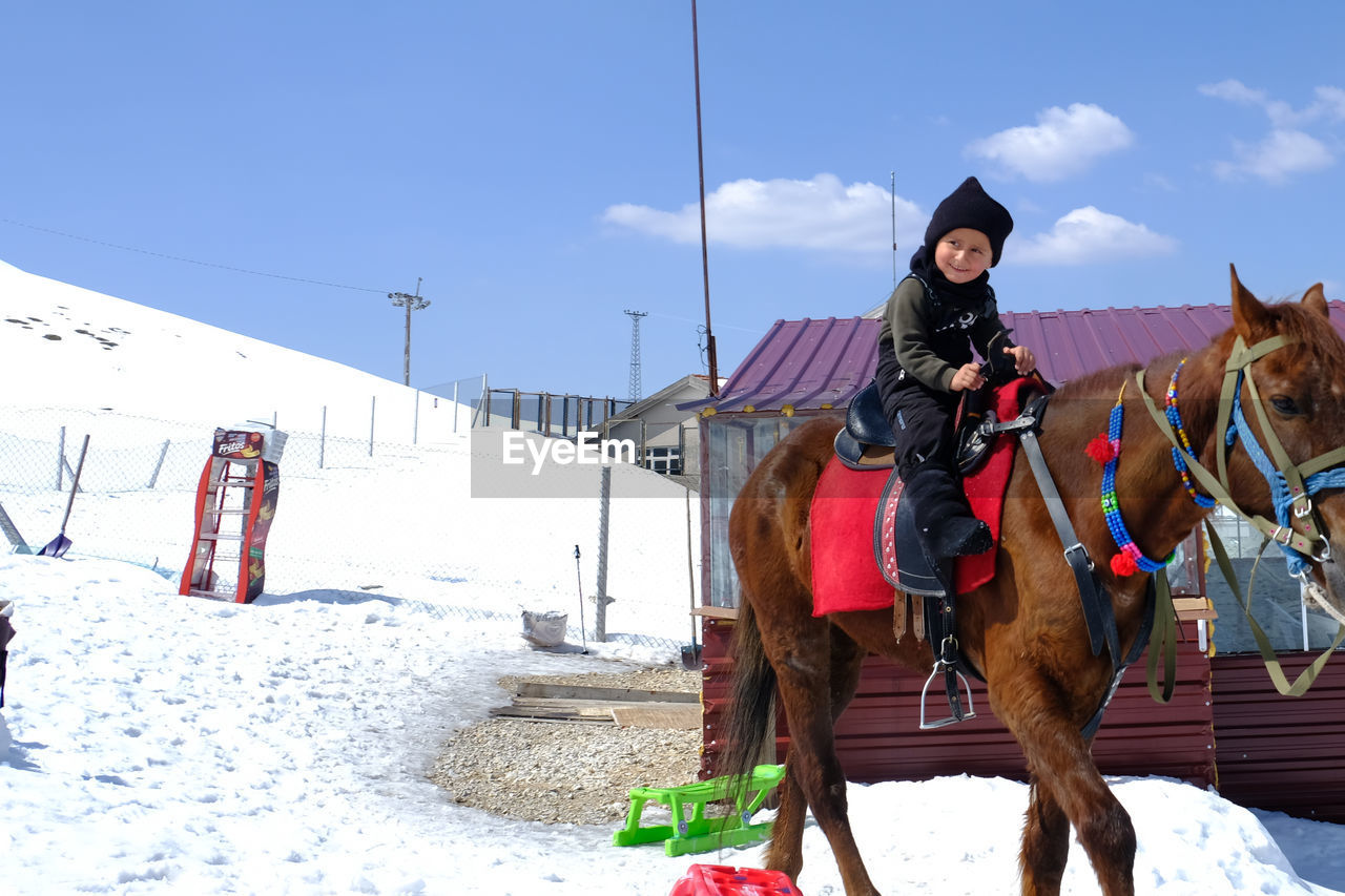 Front view of boy standing on snow covered landscape