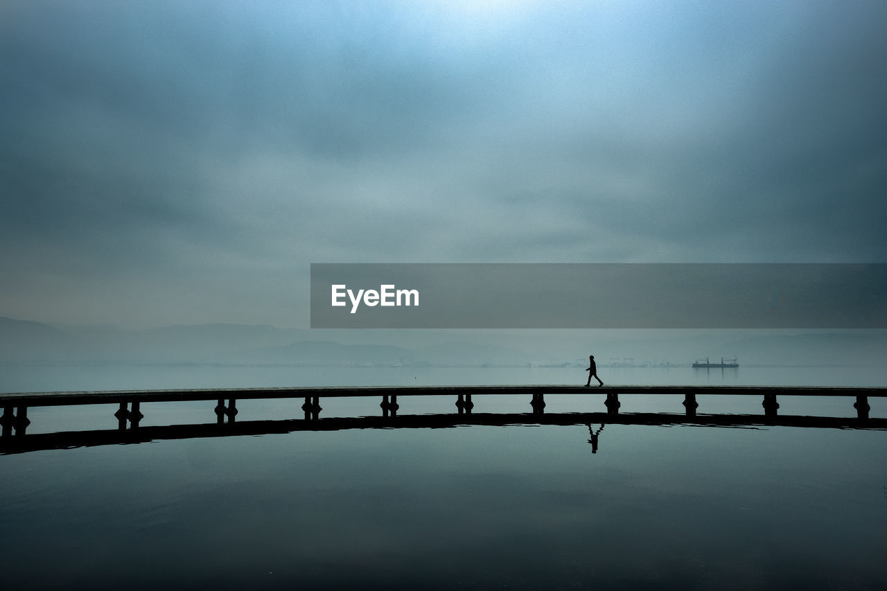 Side view of man walking on pier in lake