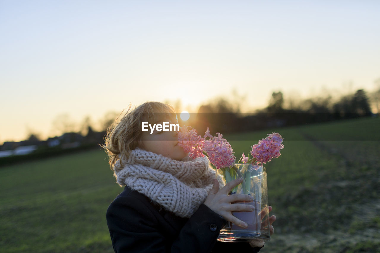 Boy on a meadow smelling hyacinth at sunset