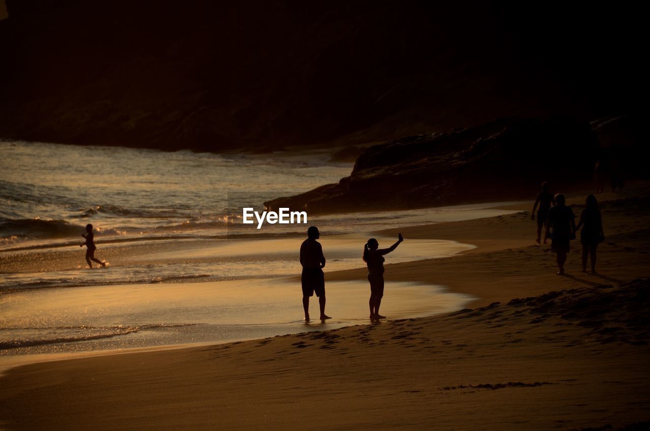 Silhouette people at beach during sunset