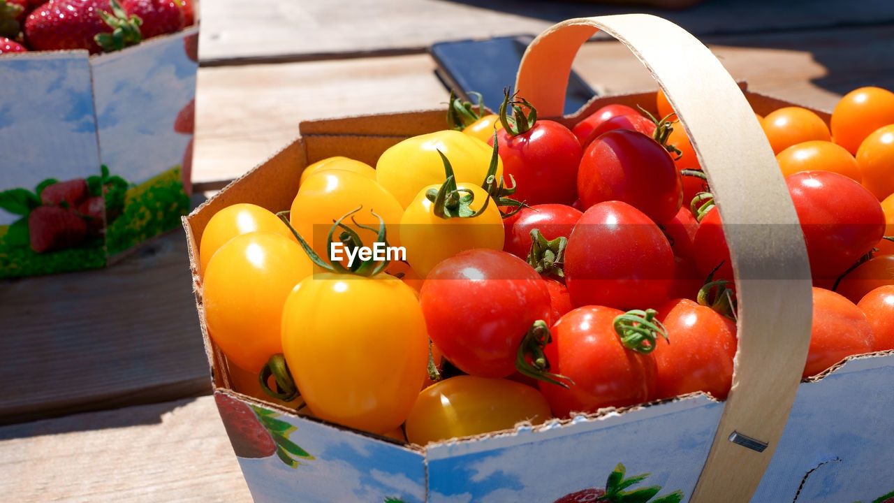 food and drink, food, healthy eating, fruit, tomato, freshness, vegetable, wellbeing, plant, red, container, produce, wood, no people, multi colored, yellow, box, nature, basket, large group of objects, crate, sunlight, table, day, close-up, outdoors, still life