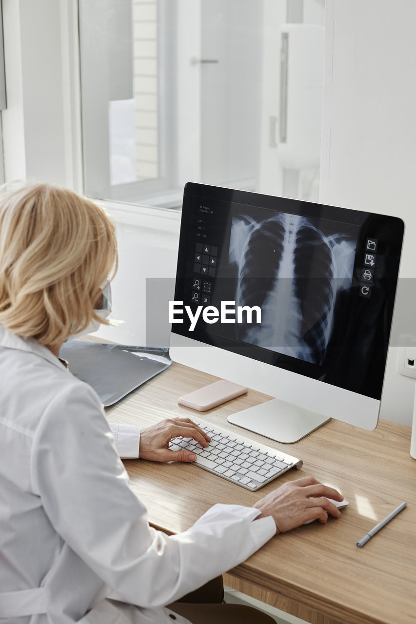 Doctor examining x-ray image on desktop pc in clinic