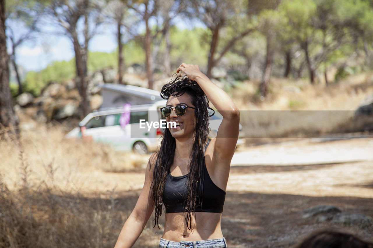 Portrait of young woman wearing sunglasses standing against car