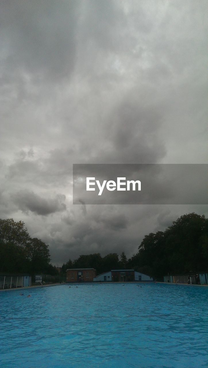 Swimming pool against cloudy sky at dusk