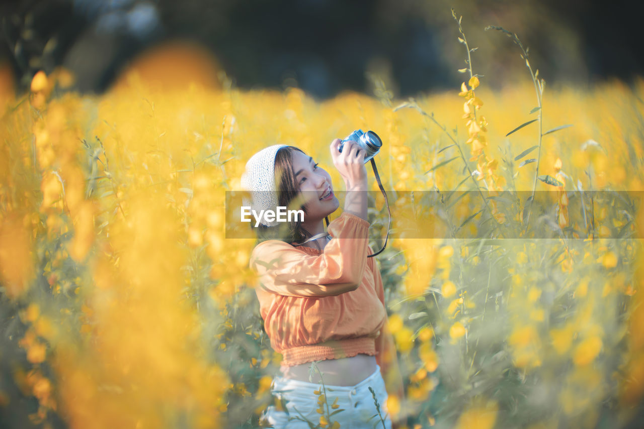 Woman photographing with camera amidst plants