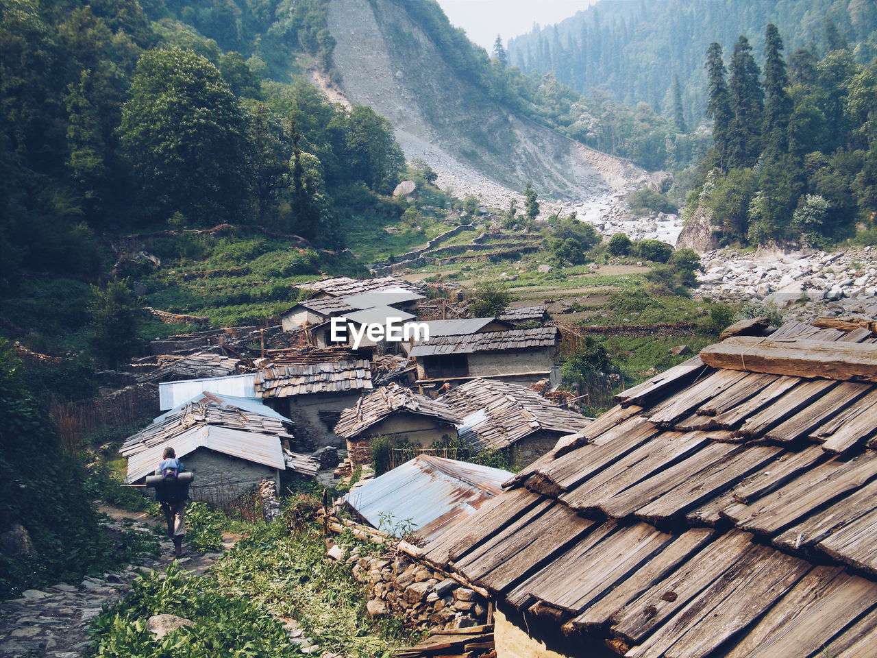 Rear view of man walking by houses against mountains