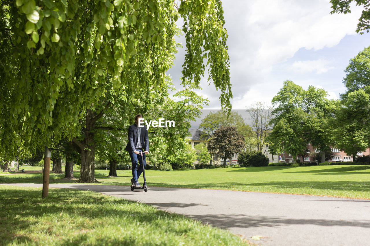 Businessman using e-scooter in a park