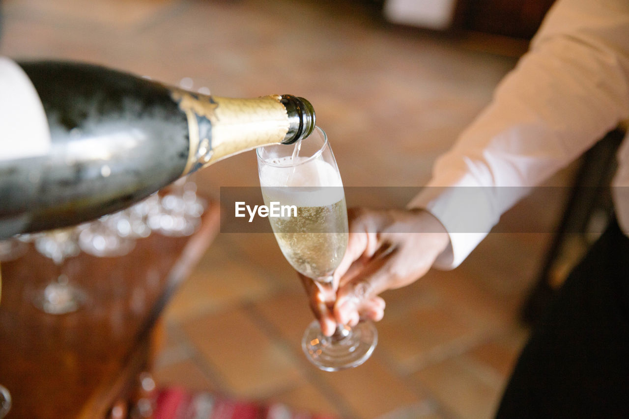 Cropped image of hand pouring champagne in glass