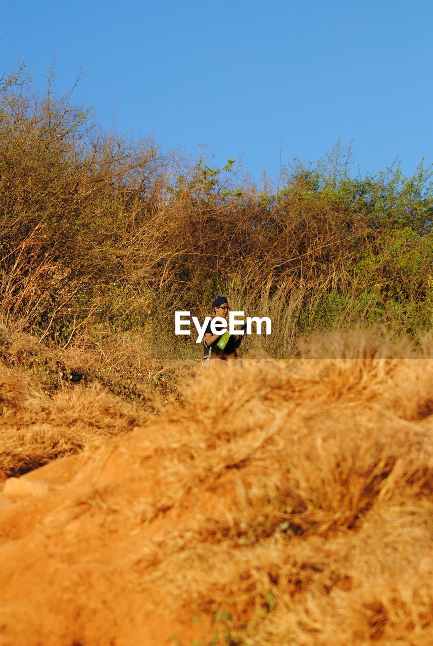 nature, plant, day, adventure, tree, extreme sports, leisure activity, men, land, sports, outdoors, one person, sky, sunlight, terrain, lifestyles, activity, beauty in nature, soil, skill, leaf, low angle view, adult, cliff