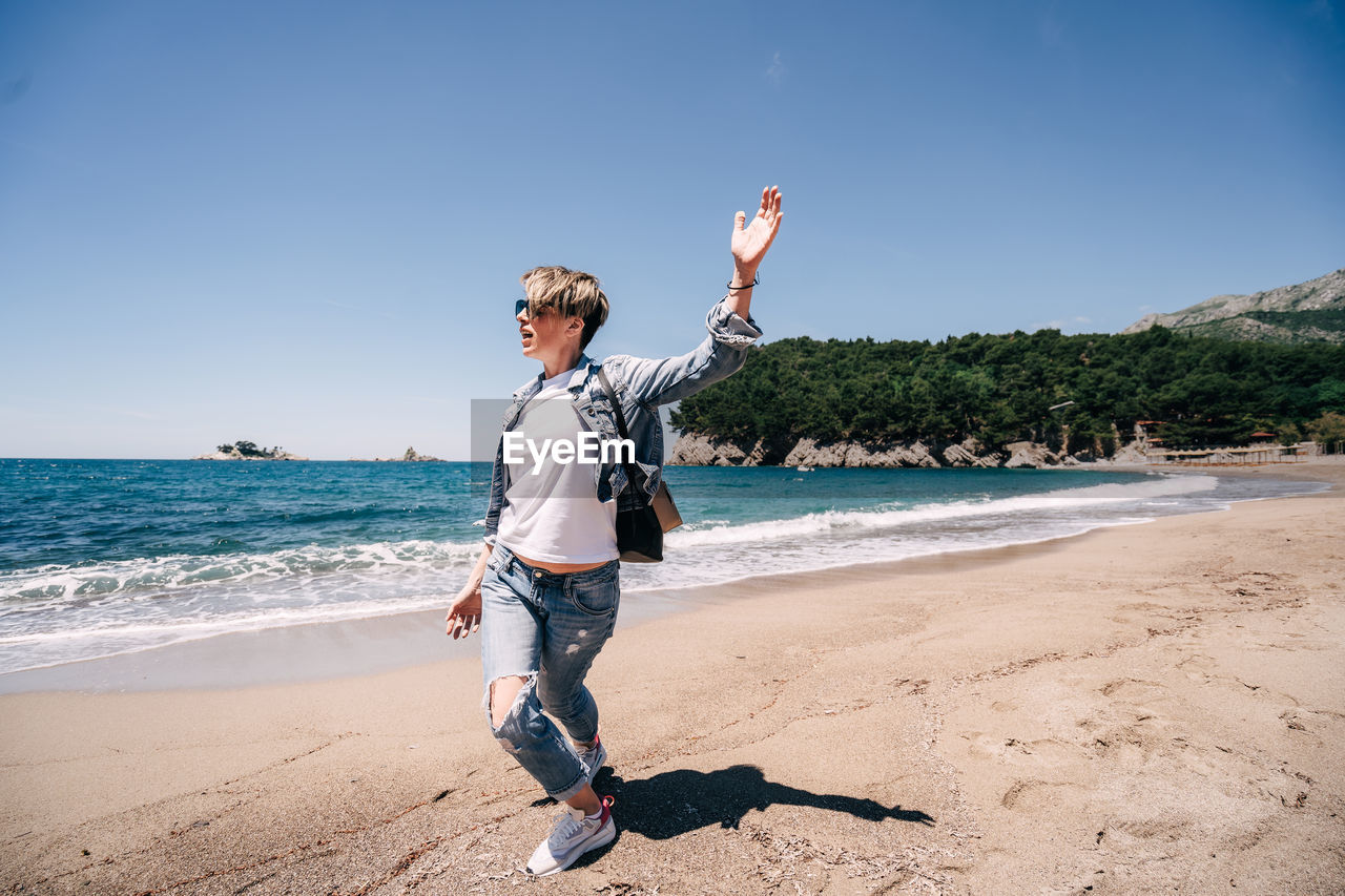 Girl with backpack on beach hands up person