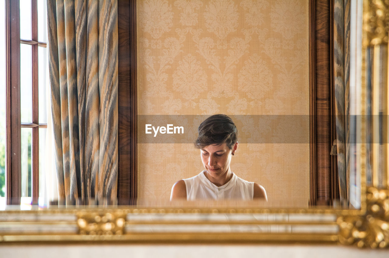 Reflection of woman with short hair seen in mirror at home