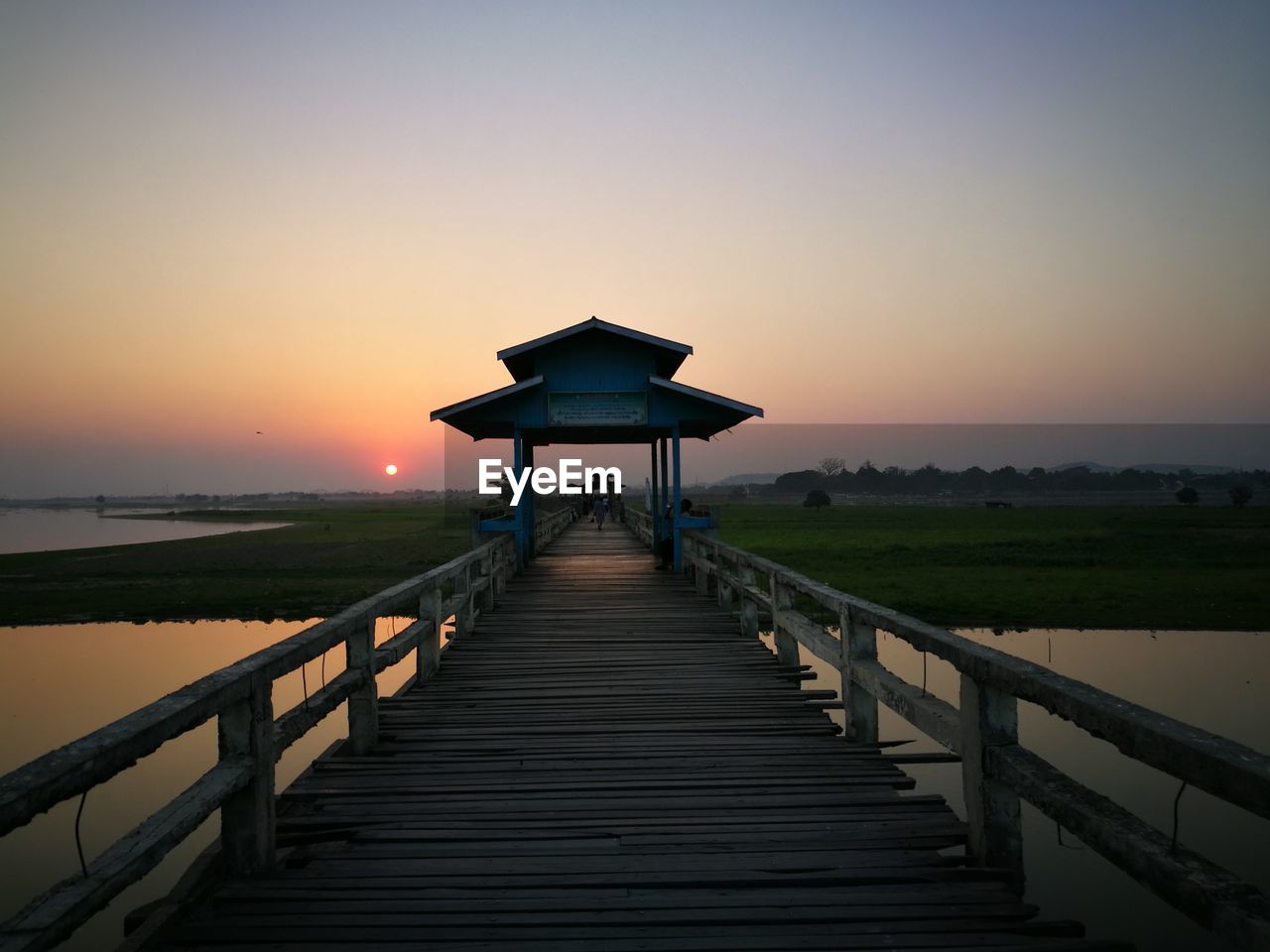 Pier over sea against clear sky during sunset