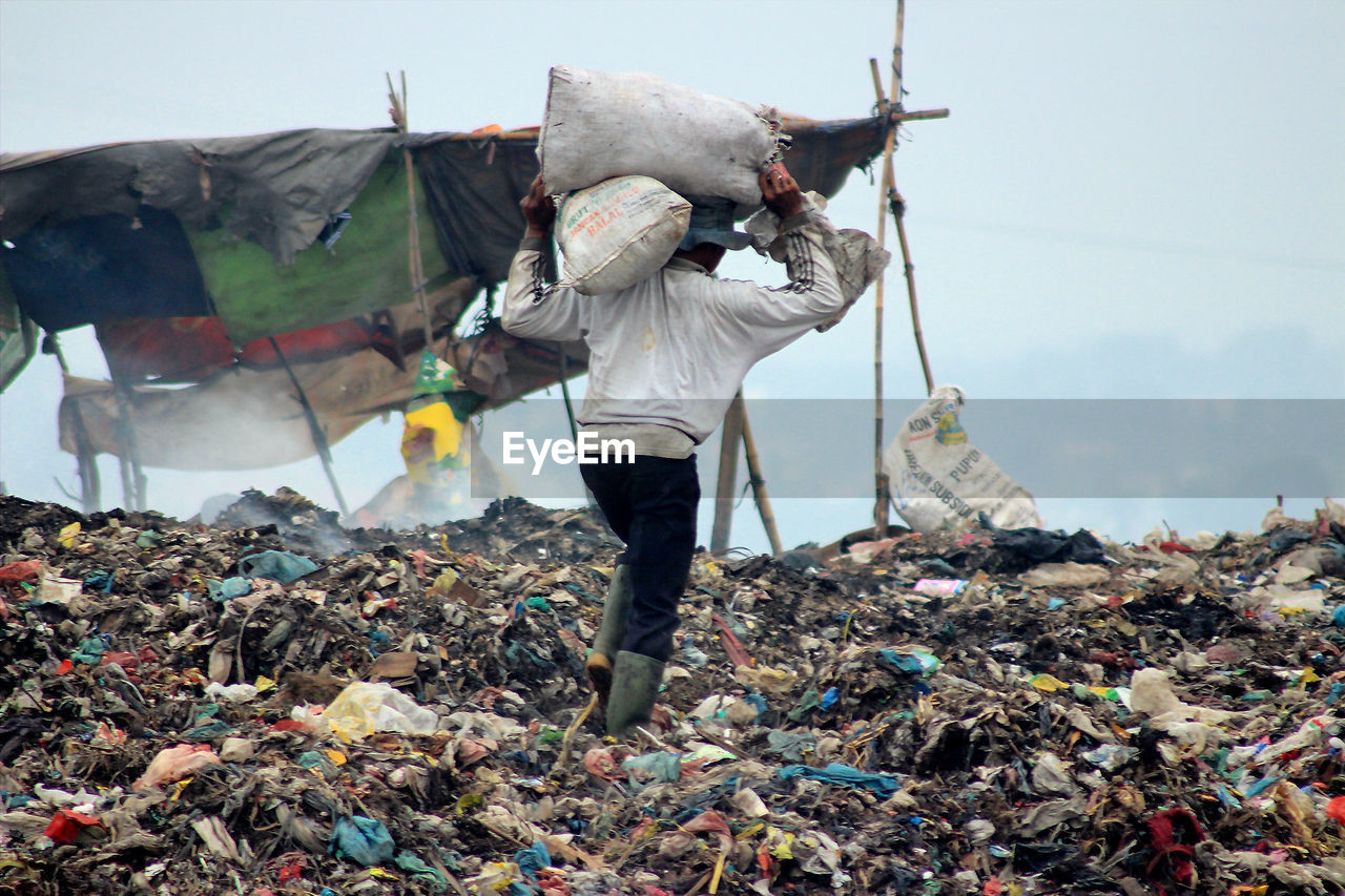 FULL LENGTH OF MAN STANDING ON GARBAGE OF FIREWOOD