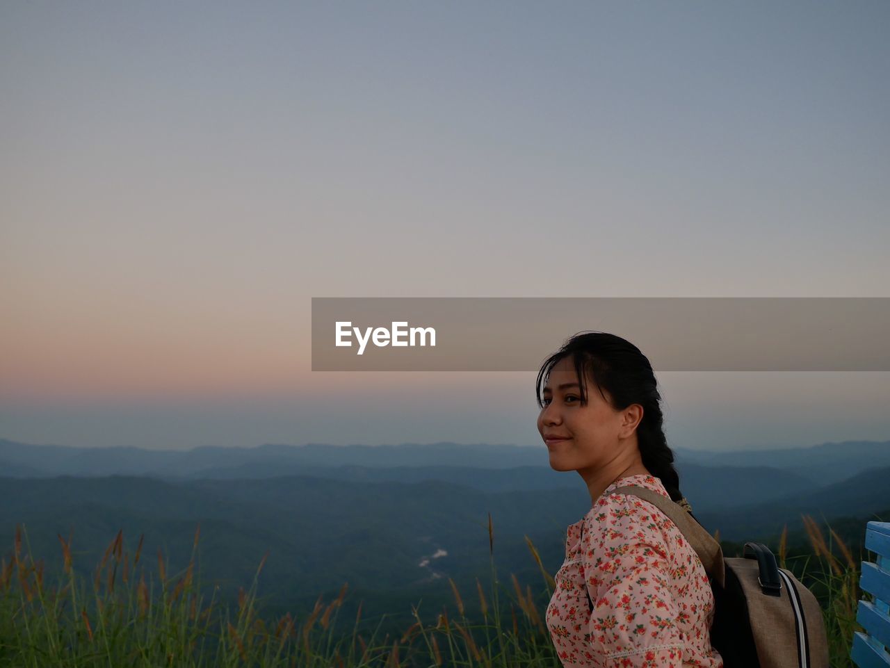 WOMAN SMILING AGAINST SKY AT SUNSET