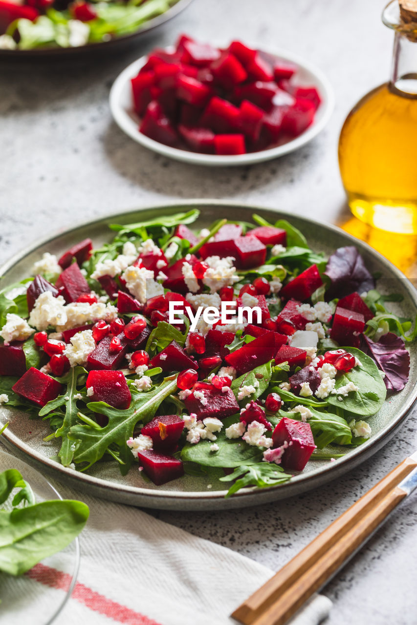 Arugula, beet and cheese salad with pomegranate and dressing on plate 