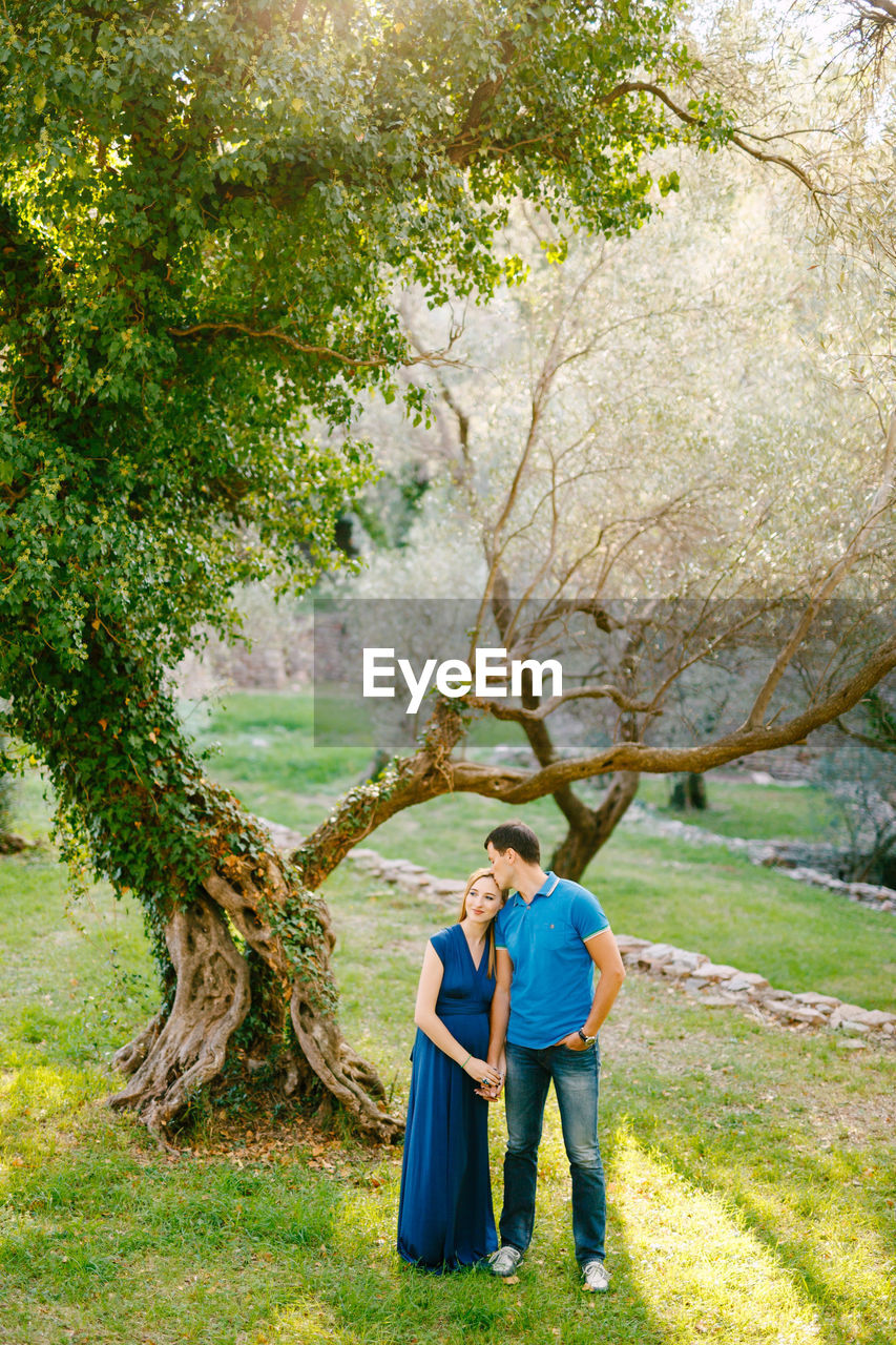 Couple kissing near tree in forest