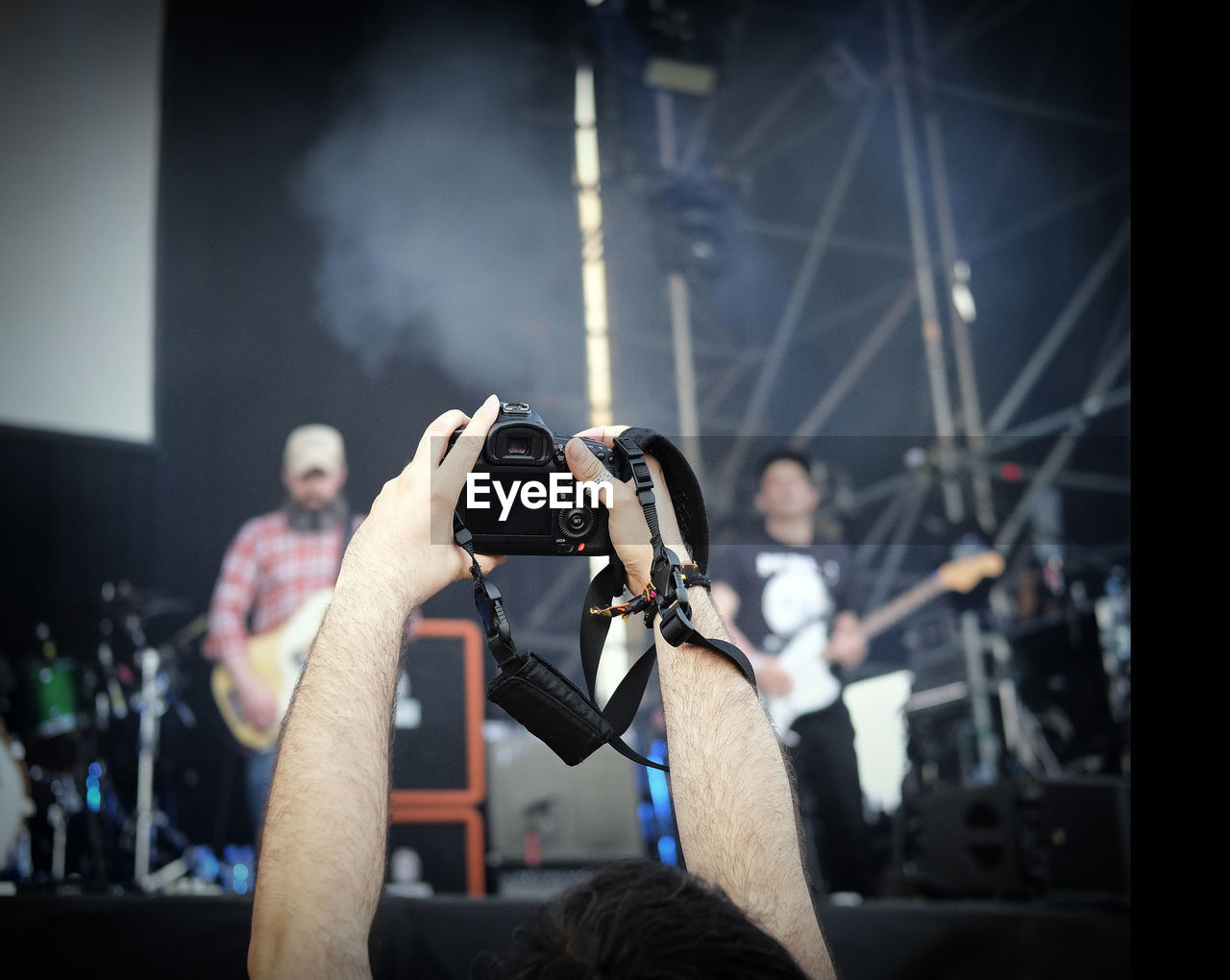 Cropped hand photographing people playing guitar