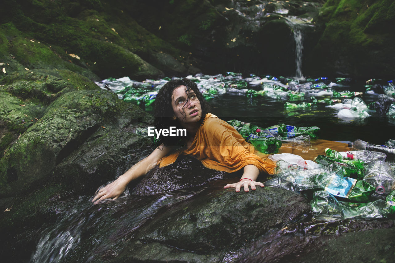 Woman amidst plastic bottles in water