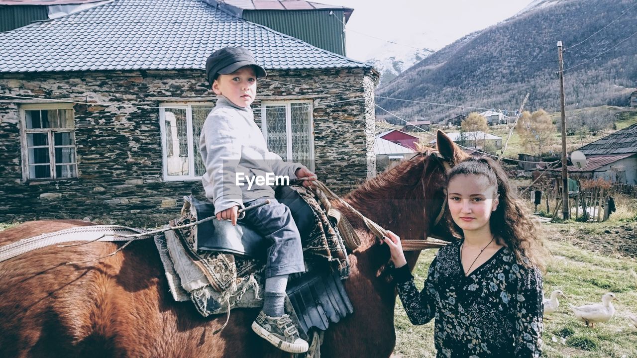 PORTRAIT OF SMILING YOUNG WOMAN WITH HORSE IN BACKGROUND