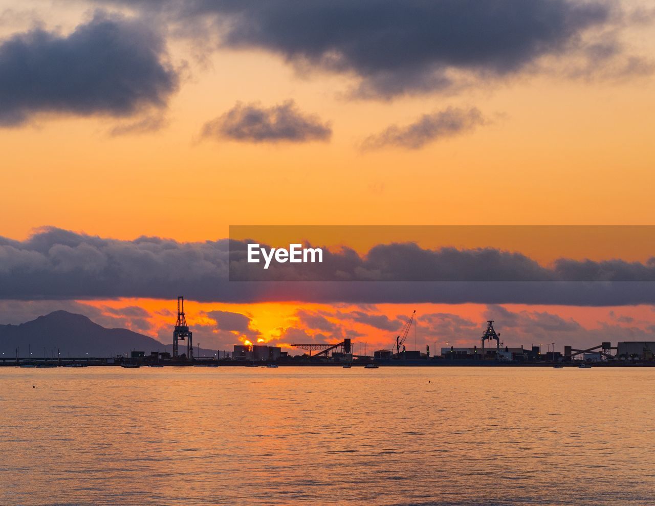 Silhouette harbor against orange sky