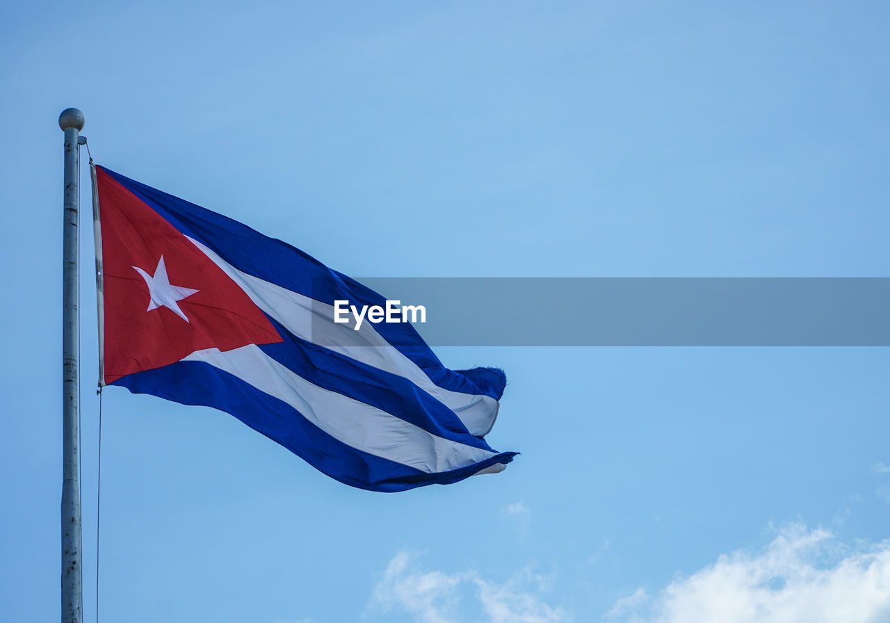 Low angle view of cuban flag against blue sky