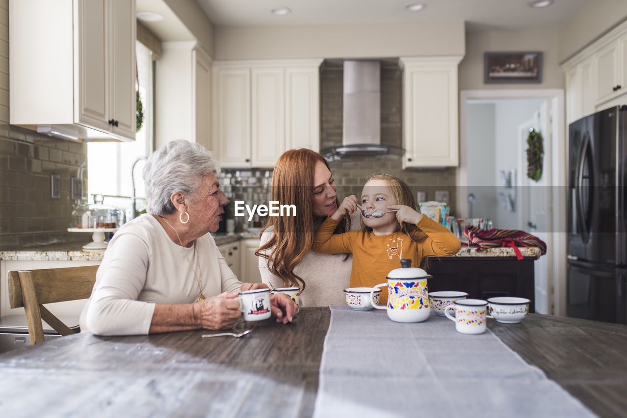 Multigenerational family playing with tea set at kitchen table
