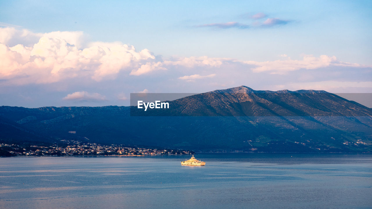 SCENIC VIEW OF SEA AGAINST MOUNTAINS