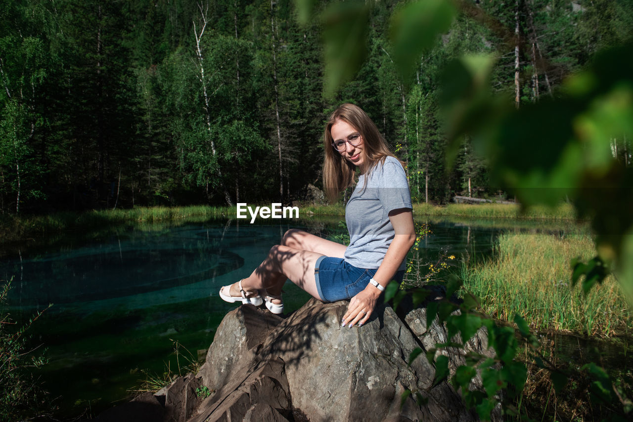 PORTRAIT OF WOMAN SITTING IN LAKE AT FOREST