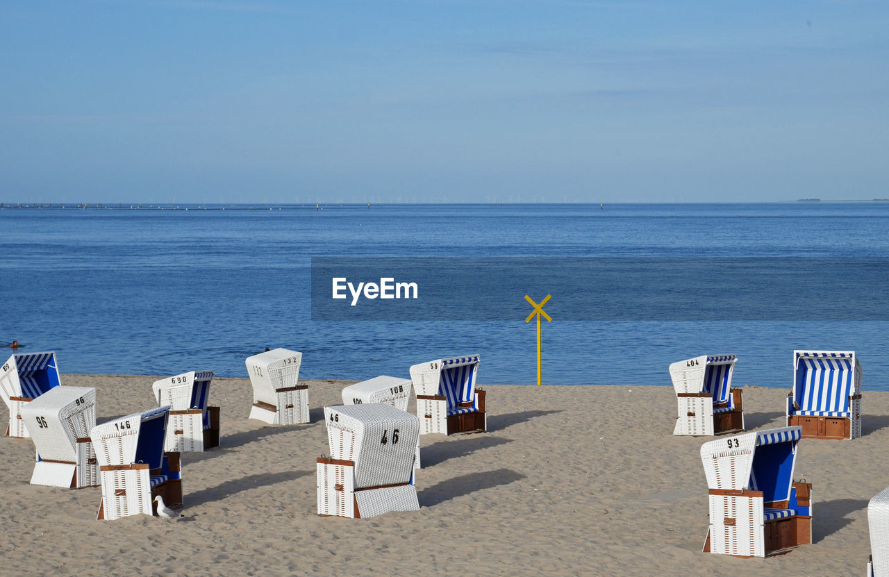 Deck chairs on beach against sky