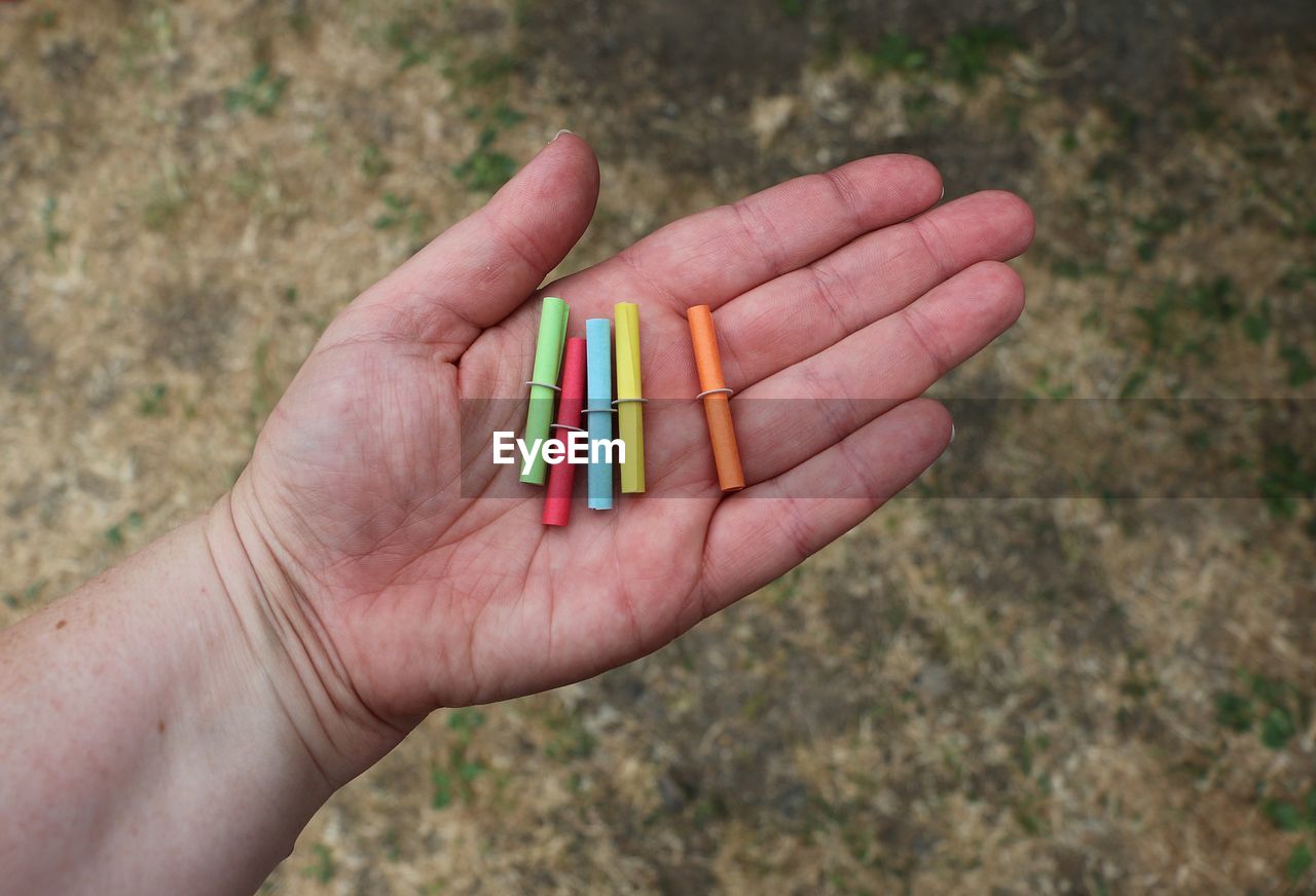 Cropped hand holding multi colored papers over footpath