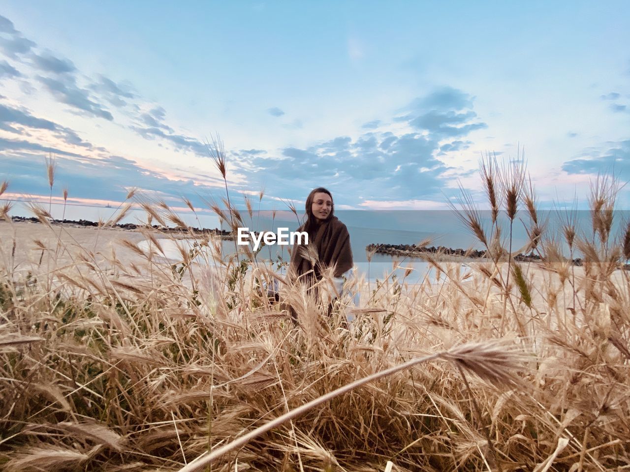 Portrait of young woman standing on field against sky