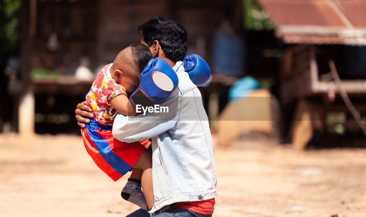 Cheerful of father and son practicing boxing on field