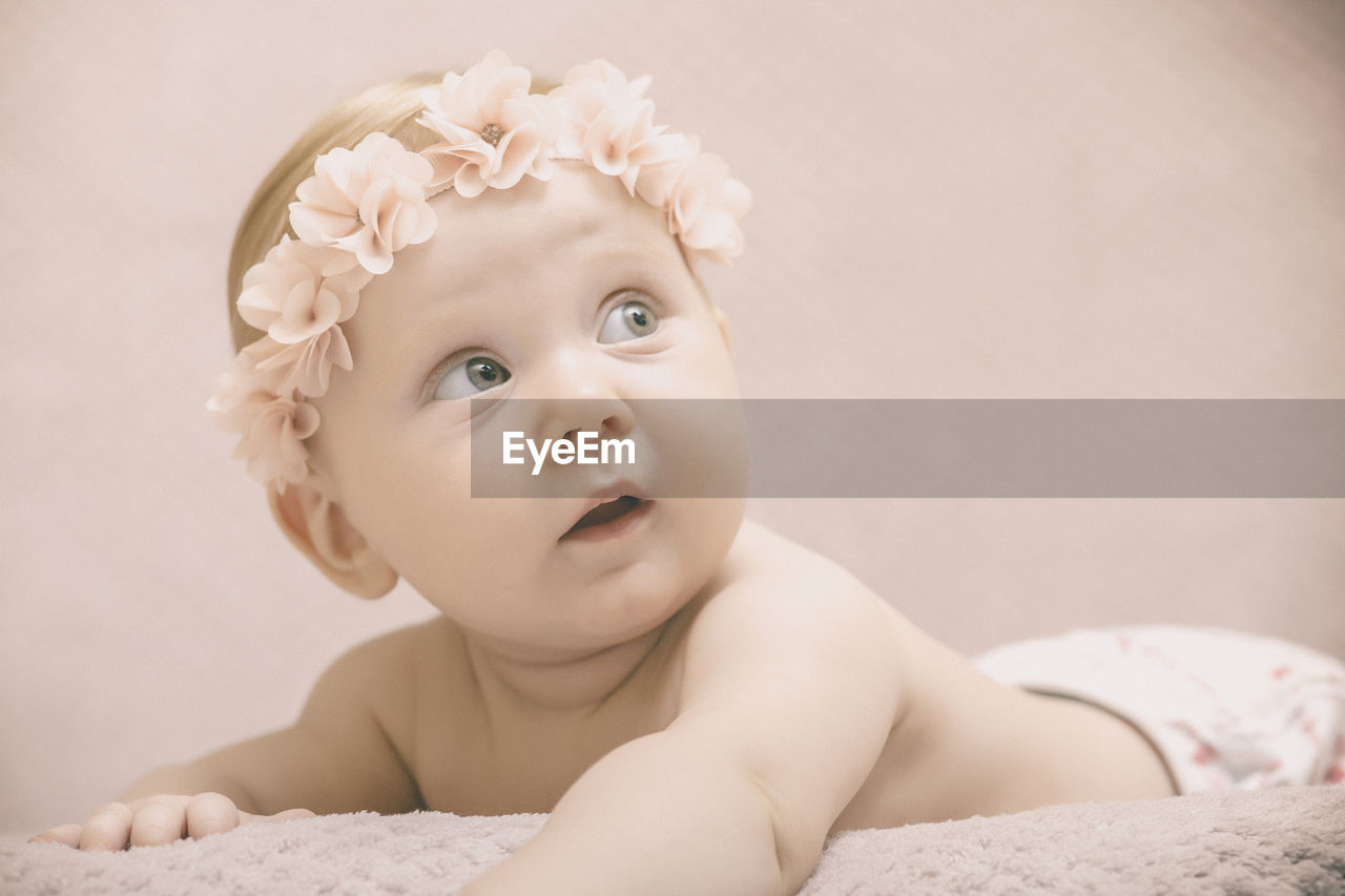 Close-up of cute baby girl wearing tiara lying on bed