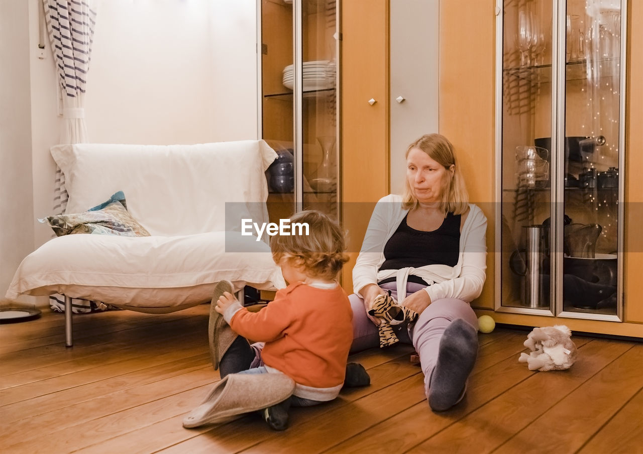 Grandmother and girl sitting on hardwood floor at home