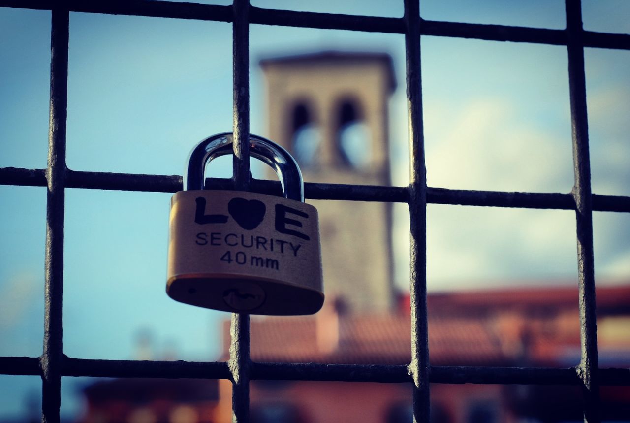 Close-up of padlock with text attached on fence