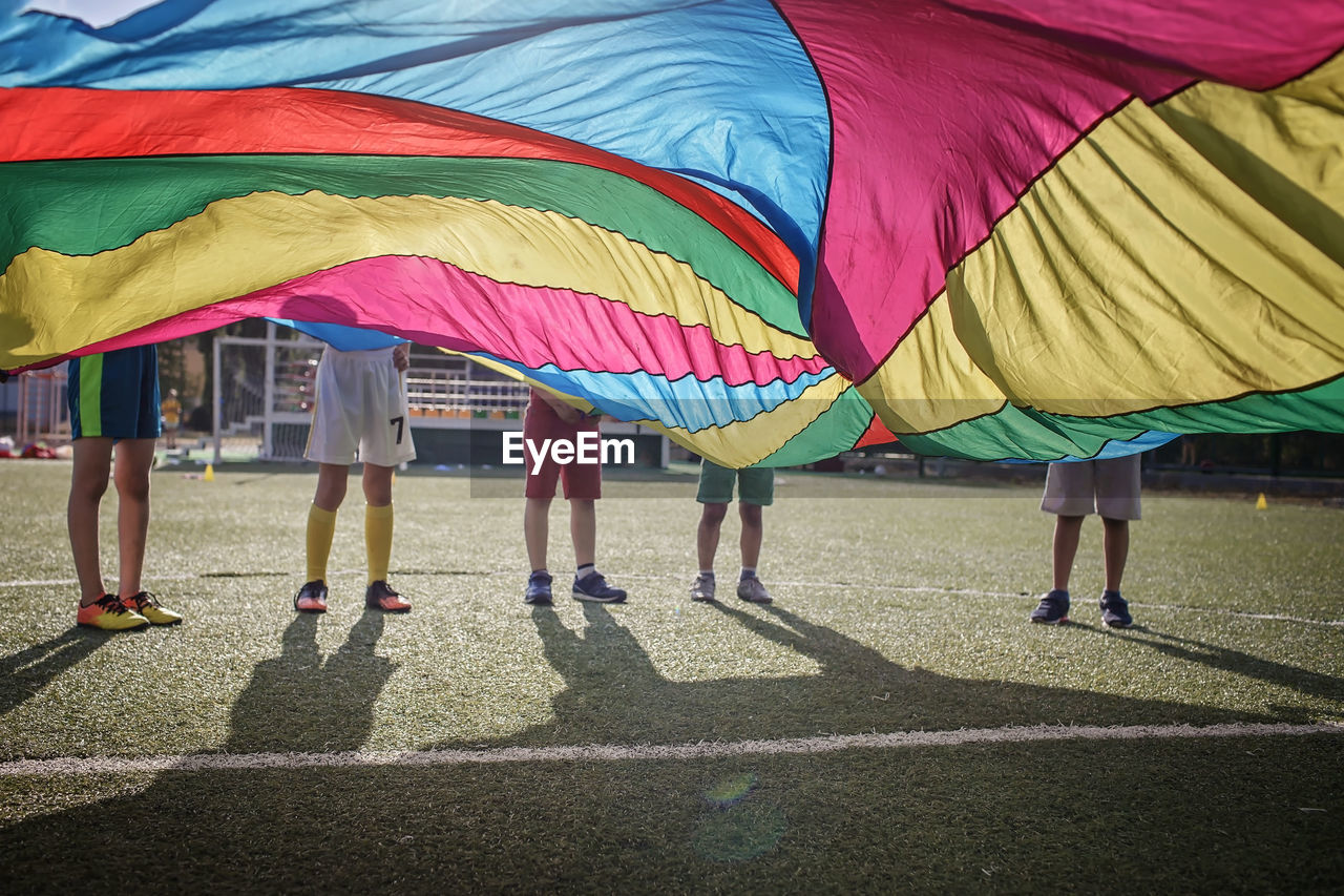 Low section of kids standing behind textile