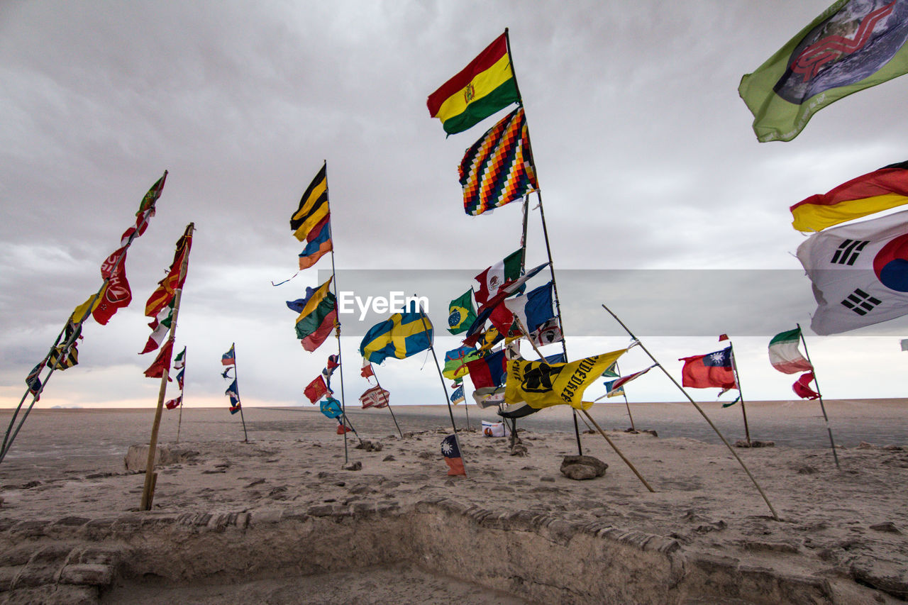 Multi colored flags on beach against sky