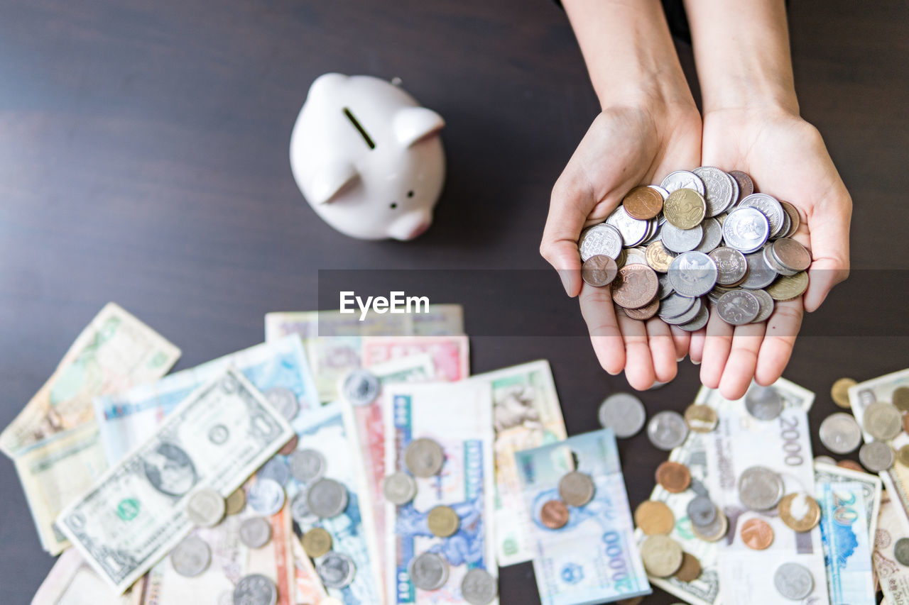 Cropped hands of woman holding money over wooden table
