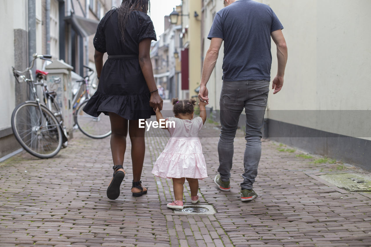 A young couple walking their daughter in european streets