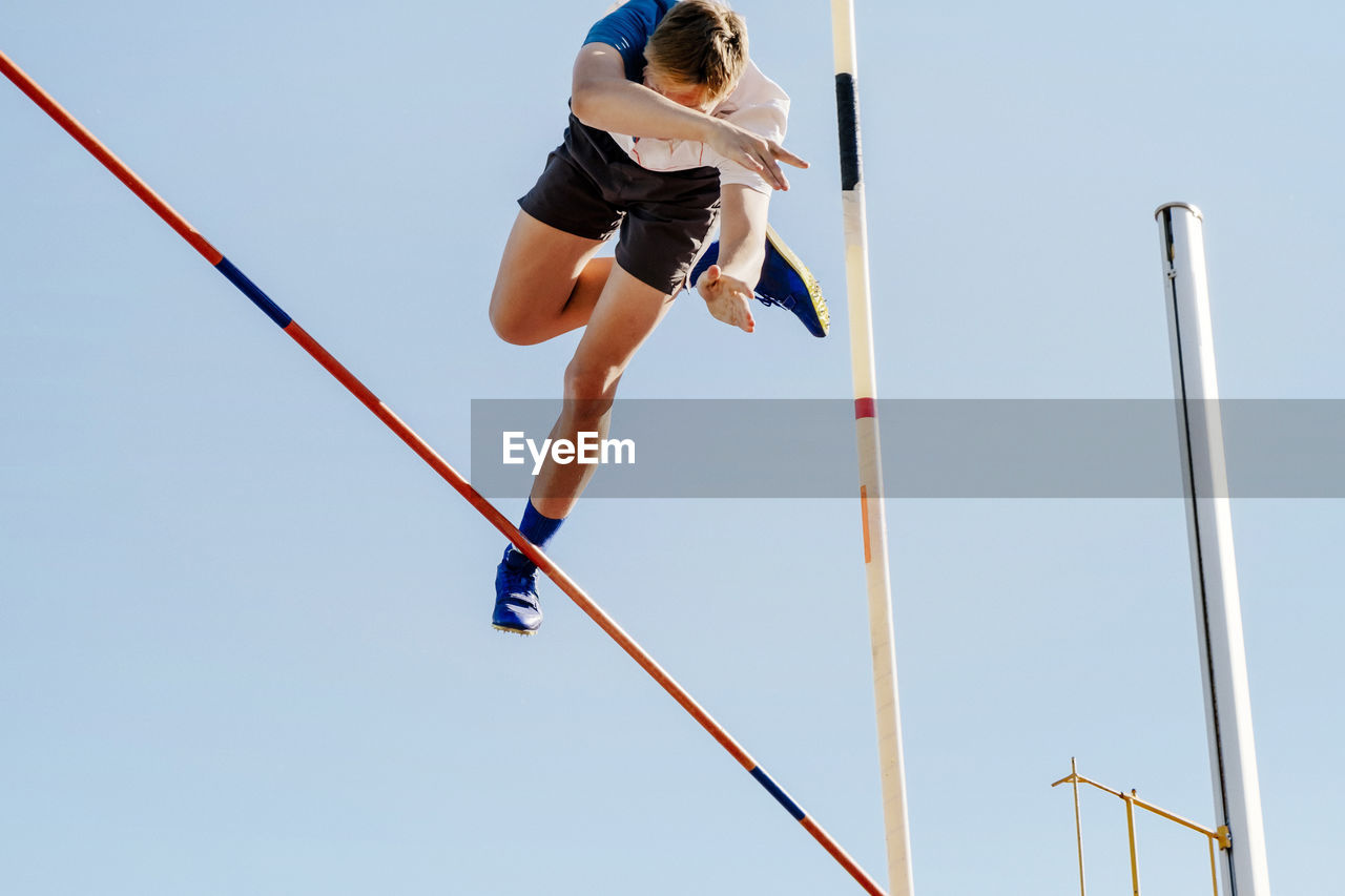 Pole vault male jumper on blue sky background