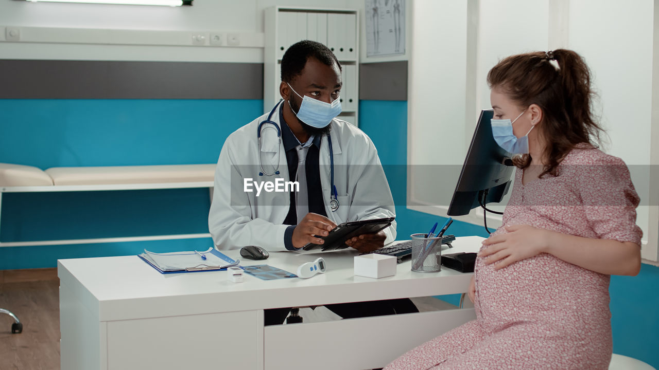 Doctor wearing mask examining patient in clinic