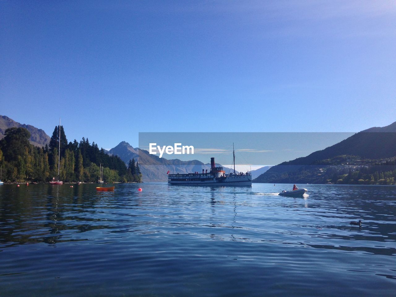 People on boat sailing in river against clear sky