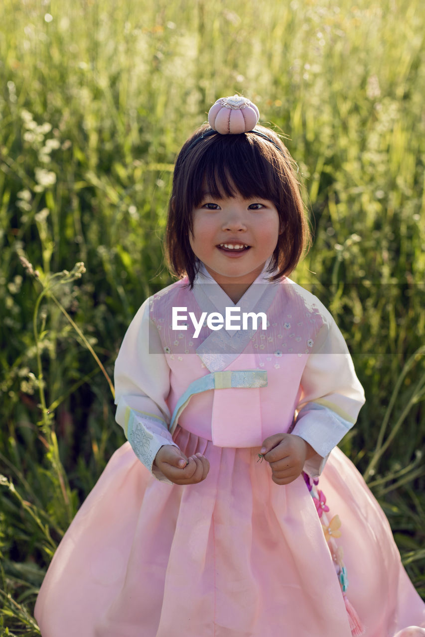 Korean national children pink costume on a four year old girl standing in a field with grass