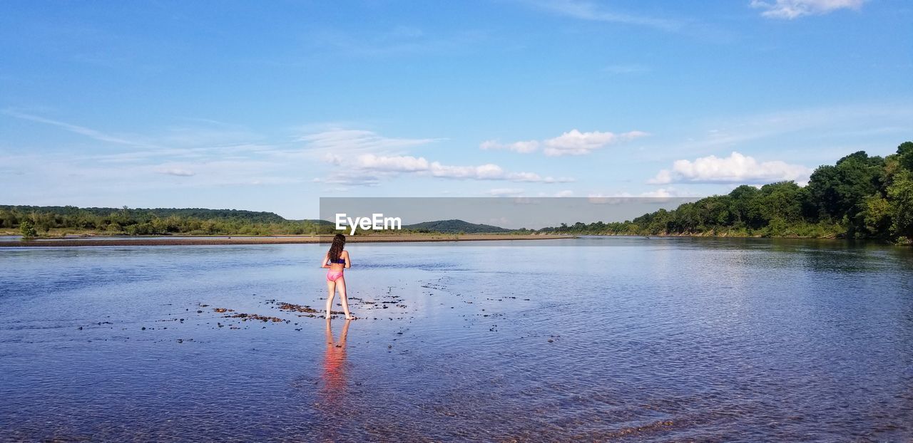 WOMAN STANDING IN WATER AGAINST SKY
