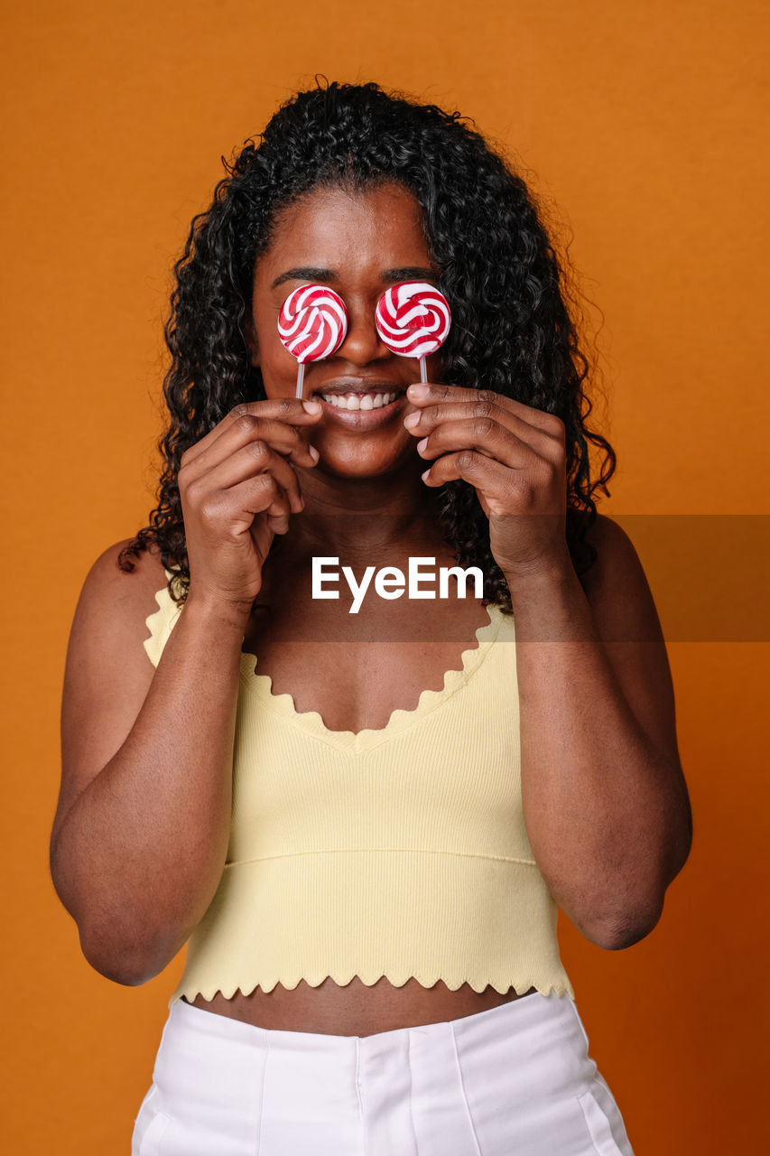 portrait of young woman wearing mask against orange background