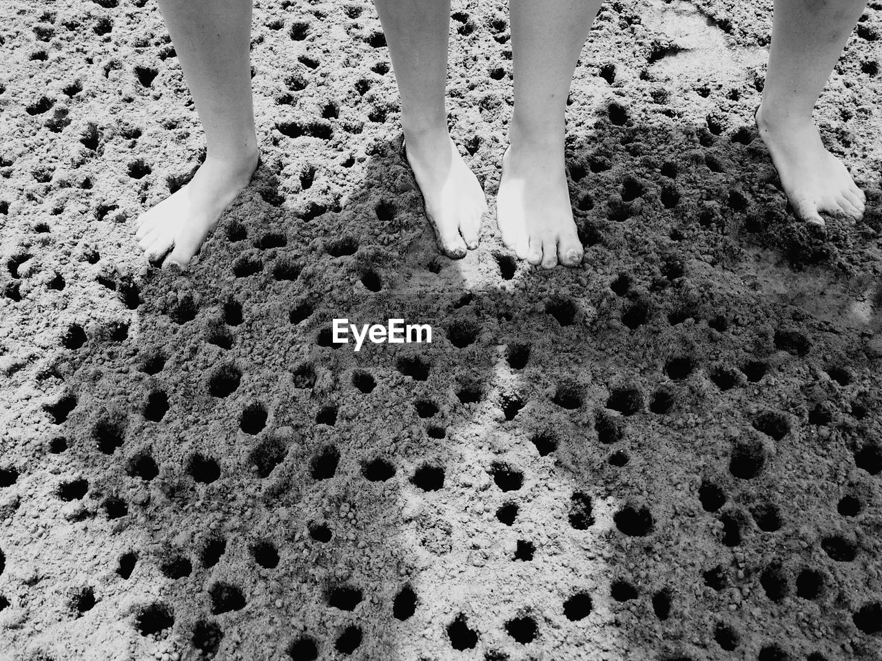 LOW SECTION OF WOMAN STANDING ON SAND